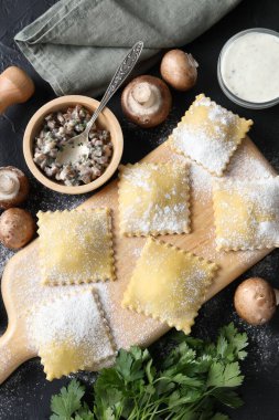 Pişmemiş ravioli, mantar ve sos siyah masada, düz yatıyordu.