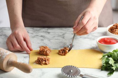 Beyaz mermer masada ravioli yapan kadın, yakın plan.