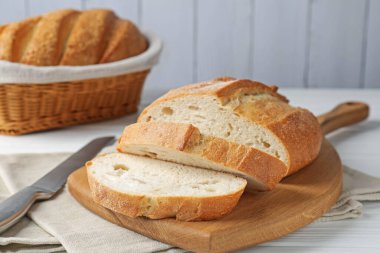 Beyaz ahşap masada ekmek ve bıçak kes, yakın plan.