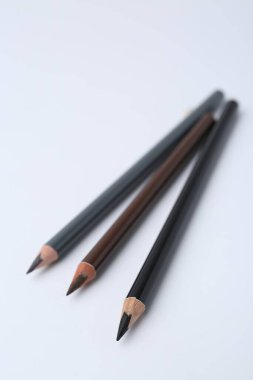 Beyaz arka planda üç farklı kaş kalemi, yakın plan.