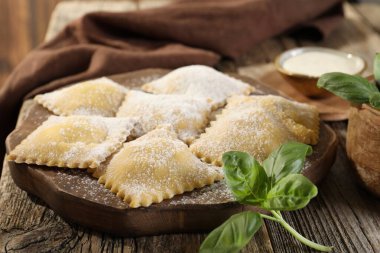 Ahşap masada pişmemiş ravioli ve fesleğen, yakın plan.