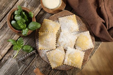 Ahşap masada pişmemiş mantı ve fesleğen.