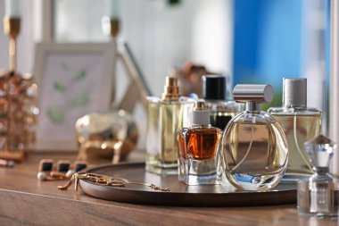 Farklı parfüm şişeleri ve aksesuarlar ahşap masada, yakın plan.