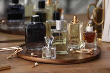 Farklı parfüm şişeleri ve aksesuarlar ahşap masada, yakın plan.
