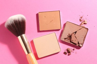 Kozmetik ürünlerinin kaplarını doldur ve pembe arka planda fırçala, düz yat