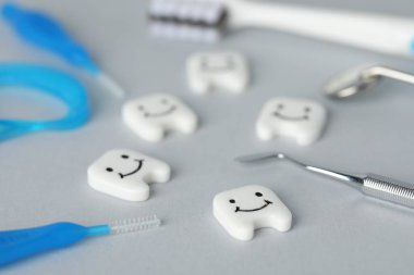 Açık gri arka planda farklı oral bakım ürünleri ve diş modelleri, yakın plan