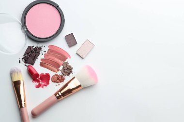 Beyaz arka planda farklı kozmetik ürünler ve makyaj fırçaları. Metin için boşluk