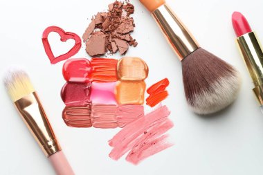 Beyaz arka planda farklı kozmetik ürünler ve makyaj fırçaları, düz yatış