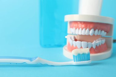 Diş macunu, gargara ve diş fırçası açık mavi arka planda, yakın plan.