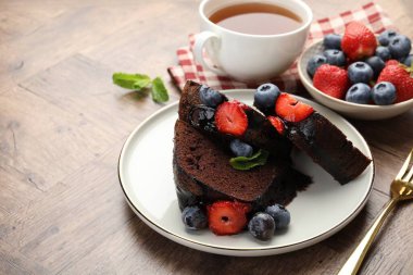 Çilekli, ahşap masadaki yaban mersinli çikolatalı kek parçaları.