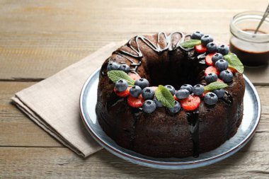 Çilekli, nane ve böğürtlenli nefis çikolatalı kek, ahşap masada, yakın plan.