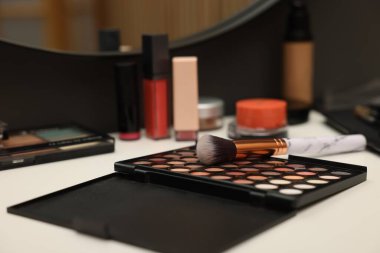 Farklı makyaj ürünleri ve tuvalet masasında fırça.
