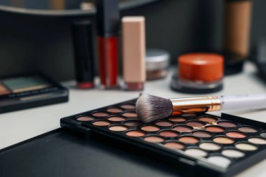 Farklı makyaj ürünleri ve tuvalet masasında fırça.