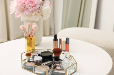 Beyaz masadaki farklı makyaj ürünlerinin olduğu tepsi. Metin için boşluk