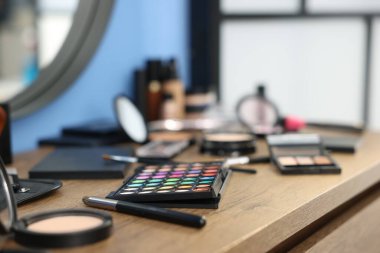 Kapalı alanda, ahşap masada farklı makyaj ürünleri.