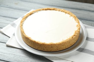Gri ahşap masada lezzetli bir cheesecake, yakın plan.