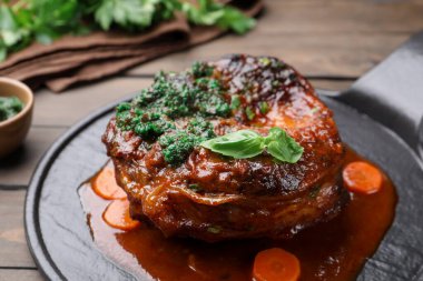 Biftek ve soslu geleneksel ossobuko tabağı ahşap masada servis edilir.