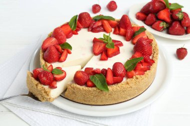 Çilekli nefis peynirli kek ve beyaz ahşap masada nane şekeri.