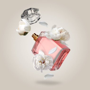 Bir şişe lüks parfüm ve açık gri arka planda şakayıklar. Çiçek aroması