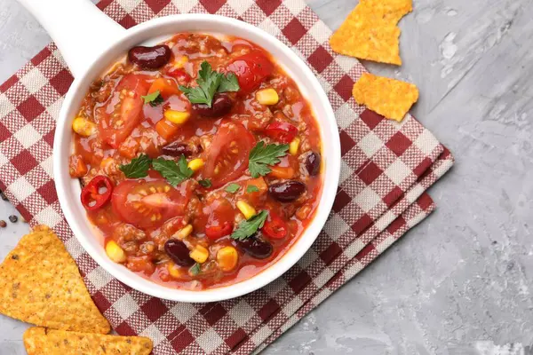 Lezzetli biberli makarna kasede ve nachos gri desenli masada, düz yerde.