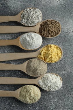 Gri masadaki kaşıklarda farklı türde un, düz.