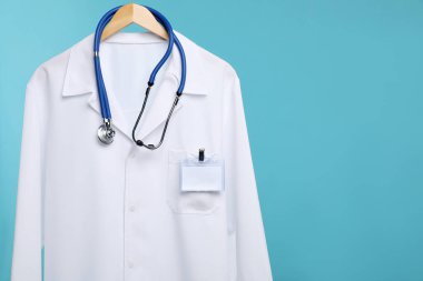 Steteskop ve rozetli doktorun ceketi mavi arka planda. Metin için boşluk