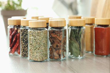 Kapalı alanda, ahşap masadaki kavanozlardaki farklı aromatik baharatlar.