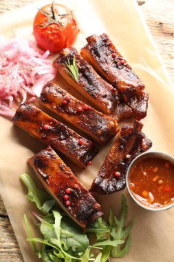 Lezzetli domuz pirzolası, sos, roka ve soğan ahşap masa, üst manzara.