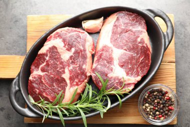 Gri masadaki fırında pişirme kabında çiğ et ve baharat parçaları.