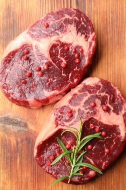 Ahşap masada çiğ et ve baharat parçaları.