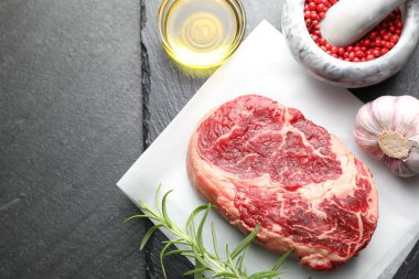 Bir parça çiğ et ve baharat siyah masada, düz yerde. Metin için boşluk