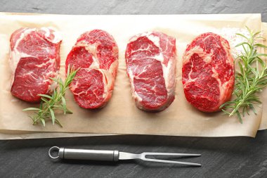 Çiğ et, baharat ve çatal parçaları siyah masaya, düz yatıyordu.