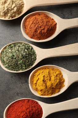 Gri masadaki kaşıklardaki farklı baharatlar düzdü.