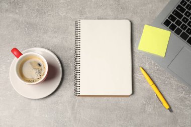 Not defteri, kalem, yapışkan not, kahve ve dizüstü bilgisayar gri masada, düz yerde.