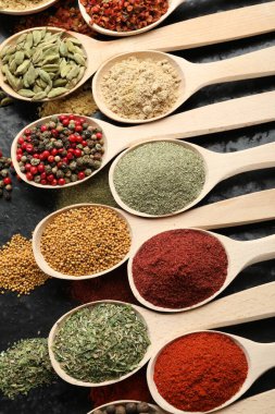 Siyah masadaki kaşıklarda bir sürü farklı baharat var.