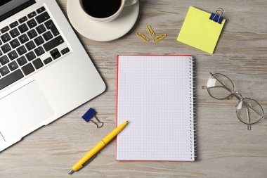 Not defteri, diğer kırtasiye malzemeleri, bardaklar, kahve ve dizüstü bilgisayar ahşap masa üzerinde, düz uzanma