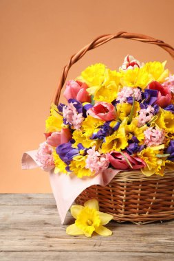 Tahta masanın üzerinde mercan zemin üzerinde güzel çiçekler olan sepet, yakın plan.