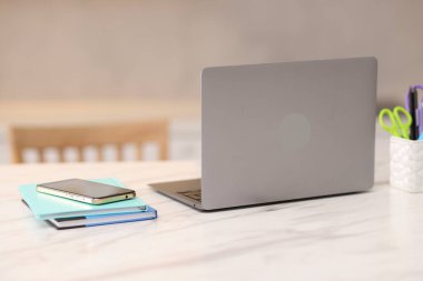 Laptop, akıllı telefon ve kırtasiye malzemeleri beyaz mermer masa içinde.
