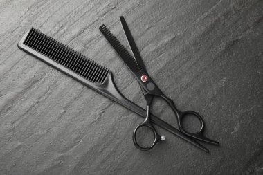 Tarak ve makas siyah masada, düz yatıyordu. Kuaför aletleri