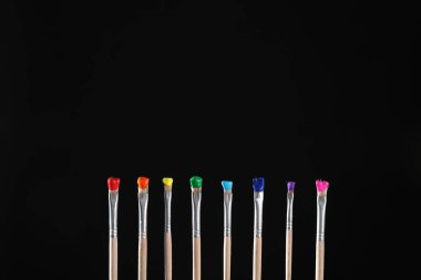 Siyah arka planda renk boyalı birçok fırça, yakın plan. Metin için boşluk