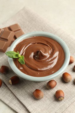 Lezzetli çikolata, parçalar, nane ve fındıklar ışık masasında, yakın plan