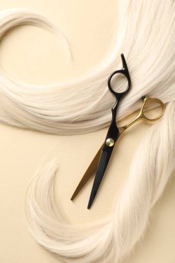 Bej arka planda saç kilitleri ve makas, düz yatış