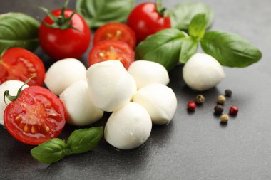 Mozzarella peyniri, domates, fesleğen ve biberler gri masada, yakın plan.