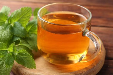 Cam bardakta Aromatik limon merhemi çayı ve masada taze yapraklar, yakın plan.