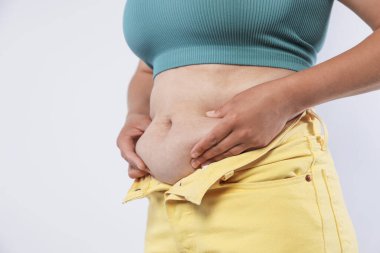 Hafif arka planda aşırı göbek yağı olan kadın, yakın plan. Aşırı kilolu