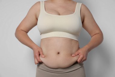 Hafif arka planda aşırı göbek yağı olan kadın, yakın plan. Aşırı kilolu