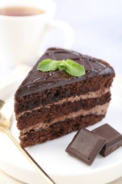 Nefis bir parça pasta, nane ve çikolata ışık masasında, yakın plan.