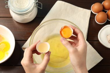 Tahta masada yumurta sarısını beyazdan ayıran kadın.