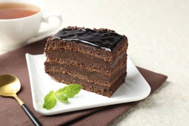 Nane, kaşık ve çayla servis edilen bir parça çikolatalı kek, yakın plan.