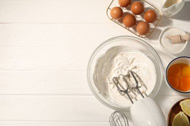 Beyaz ahşap masada çırpılmış krema, yumurta ve diğer ürünlerle karıştırıcı. Metin için boşluk